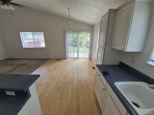 894 S Krameria St, Denver, CO 80224 - kitchen with a sink, dark countertops, vaulted ceiling, light wood finished floors, and a ceiling fan