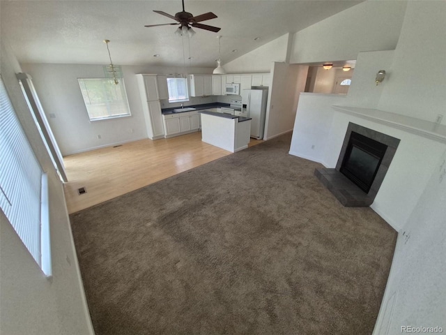 894 S Krameria St, Denver, CO 80224 - unfurnished living room with light colored carpet, a ceiling fan, vaulted ceiling, a glass covered fireplace, and a sink