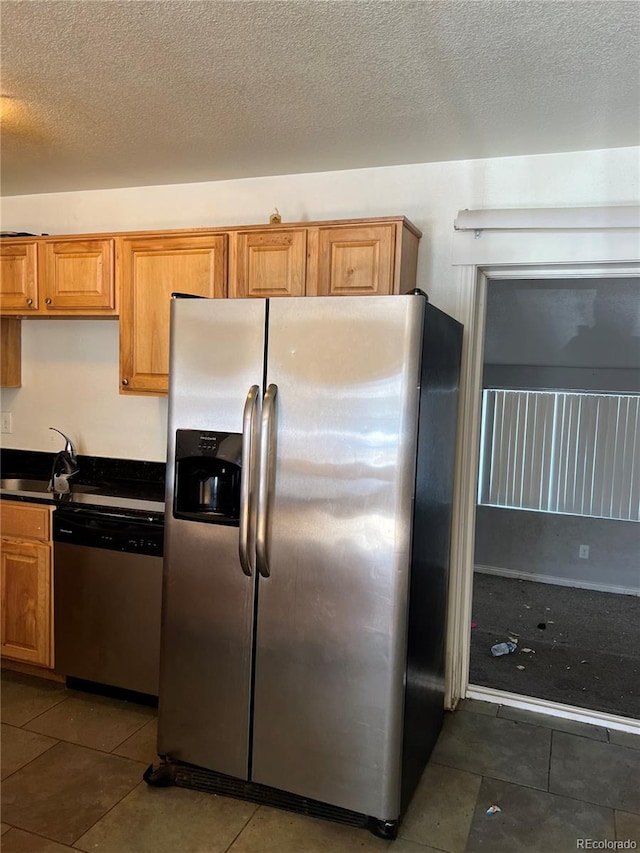 kitchen featuring sink, stainless steel appliances, dark tile floors, and a textured ceiling