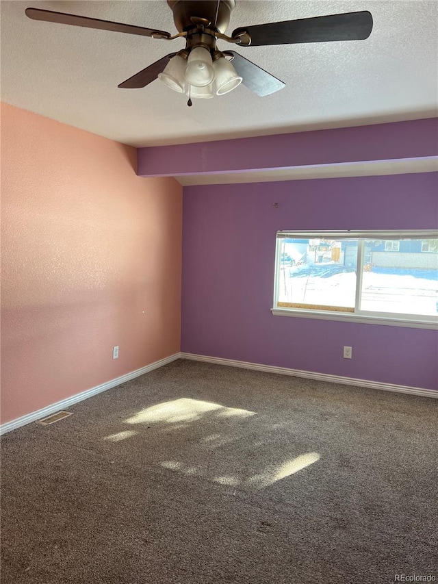 empty room featuring ceiling fan, a textured ceiling, and carpet