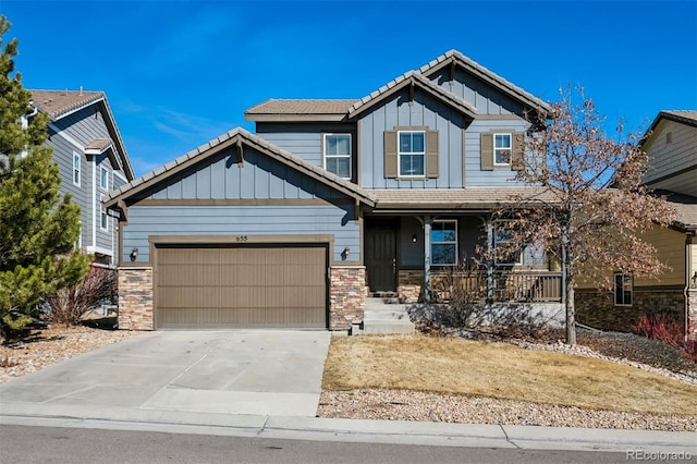 craftsman-style house with a garage, concrete driveway, stone siding, covered porch, and board and batten siding