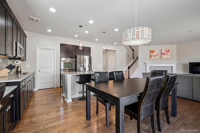 dining area with recessed lighting, a fireplace, visible vents, stairway, and light wood finished floors