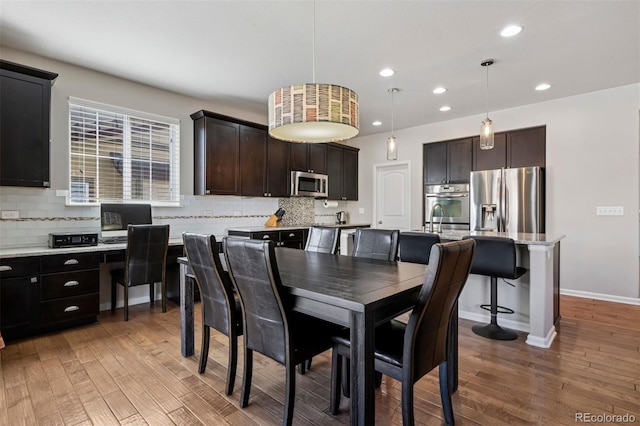 dining room featuring baseboards, light wood-type flooring, and recessed lighting