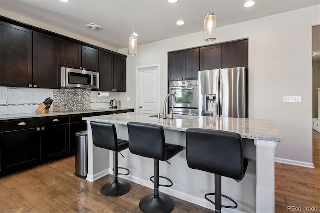 kitchen featuring a sink, a breakfast bar, stainless steel appliances, and decorative backsplash