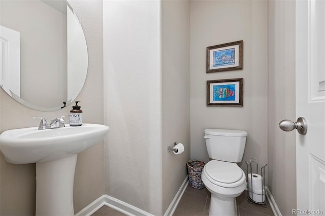 bathroom featuring tile patterned flooring, toilet, and baseboards