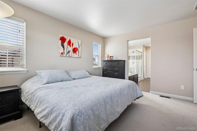 carpeted bedroom with visible vents, baseboards, and ensuite bathroom