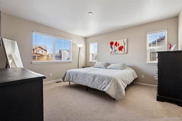 bedroom with visible vents, multiple windows, baseboards, and light colored carpet