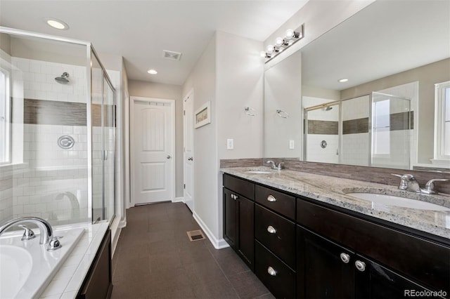 bathroom featuring a stall shower, a garden tub, and a sink