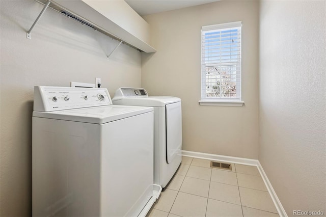 clothes washing area featuring laundry area, baseboards, visible vents, washer and dryer, and light tile patterned flooring