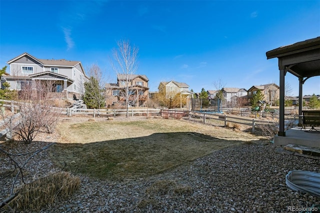 view of yard with a trampoline, a residential view, and fence