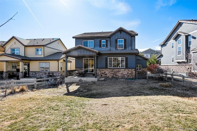 rear view of property featuring stone siding, board and batten siding, a patio area, and fence