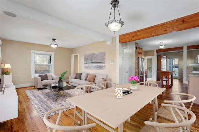 dining room with beam ceiling and wood-type flooring