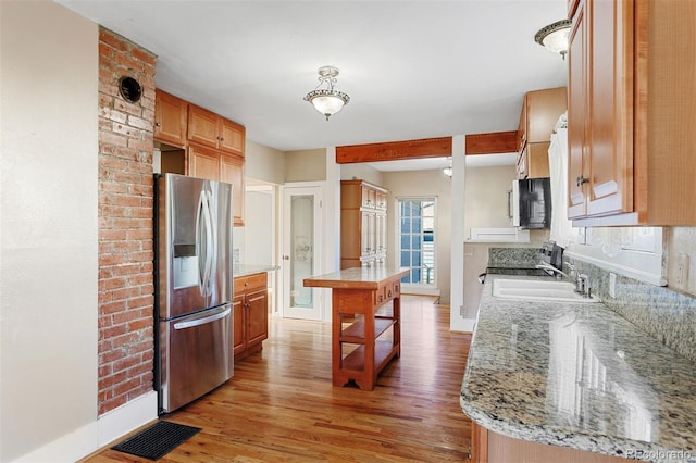 kitchen with hardwood / wood-style floors, sink, a kitchen island, stainless steel fridge with ice dispenser, and a breakfast bar area