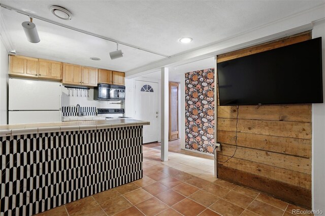 kitchen featuring tile countertops, light brown cabinets, track lighting, white refrigerator, and electric stove