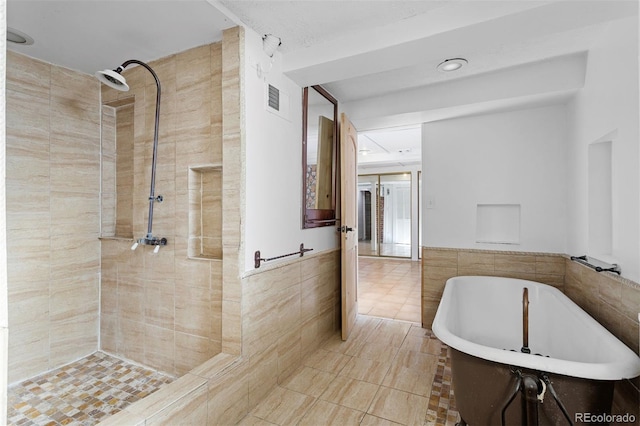 bathroom featuring tile patterned flooring, plus walk in shower, and tile walls