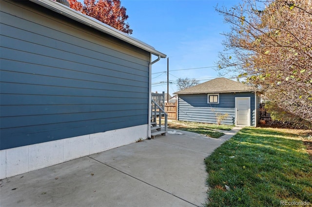 view of side of property featuring a patio area, a yard, and an outdoor structure