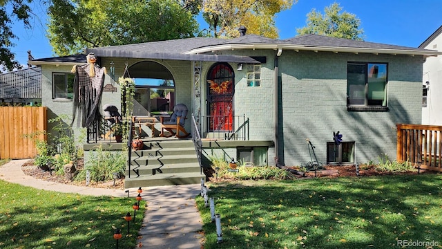 view of front of house with a front yard, brick siding, and fence