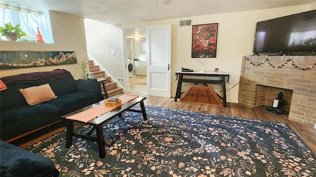 living room featuring hardwood / wood-style flooring, washer / dryer, and a fireplace