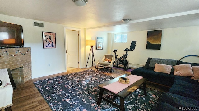 living room with wood-type flooring, a fireplace, and a textured ceiling