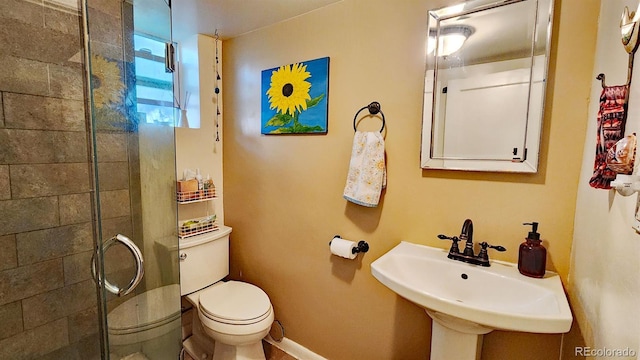 bathroom featuring toilet, a shower with door, and sink