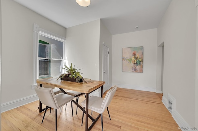 dining area featuring visible vents, baseboards, and light wood finished floors