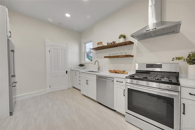 kitchen featuring a sink, light countertops, appliances with stainless steel finishes, white cabinetry, and wall chimney exhaust hood