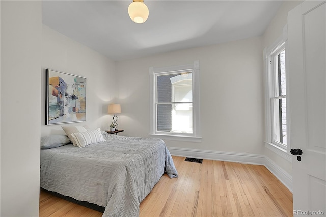 bedroom with visible vents, baseboards, and wood finished floors