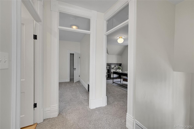 hall featuring lofted ceiling, light colored carpet, baseboards, and visible vents