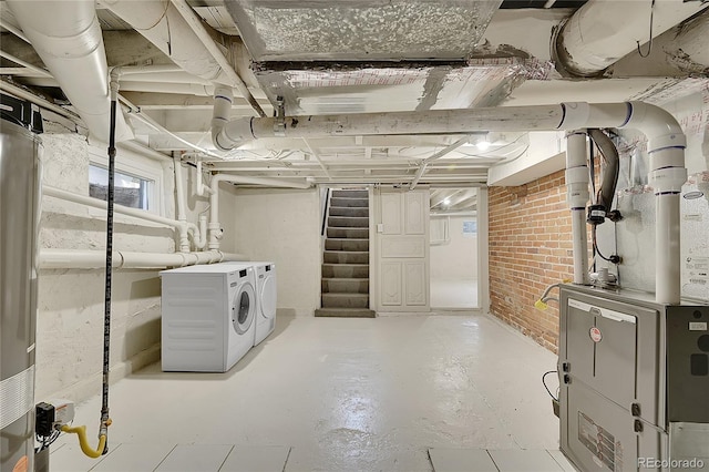 below grade area with washer and clothes dryer, heating unit, brick wall, and stairs