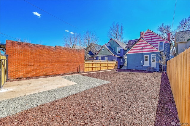 view of yard with a fenced backyard, central air condition unit, and a patio