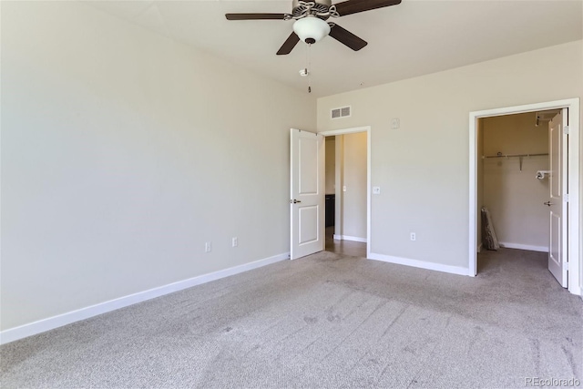 unfurnished bedroom with a spacious closet, light colored carpet, ceiling fan, and a closet