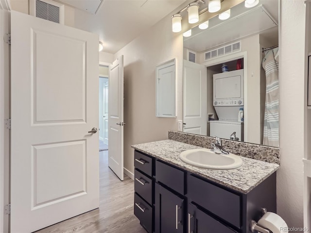 bathroom with vanity, stacked washer / drying machine, and hardwood / wood-style flooring