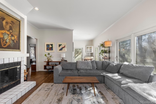 living area featuring baseboards, a tile fireplace, wood finished floors, crown molding, and recessed lighting