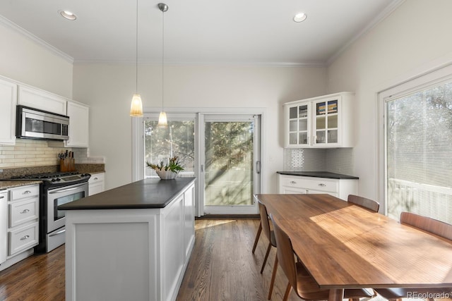 kitchen featuring dark countertops, white cabinetry, appliances with stainless steel finishes, and glass insert cabinets