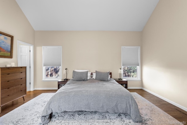 bedroom with lofted ceiling, baseboards, and wood finished floors