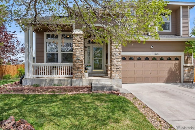 view of front of home with covered porch, a garage, driveway, and stone siding