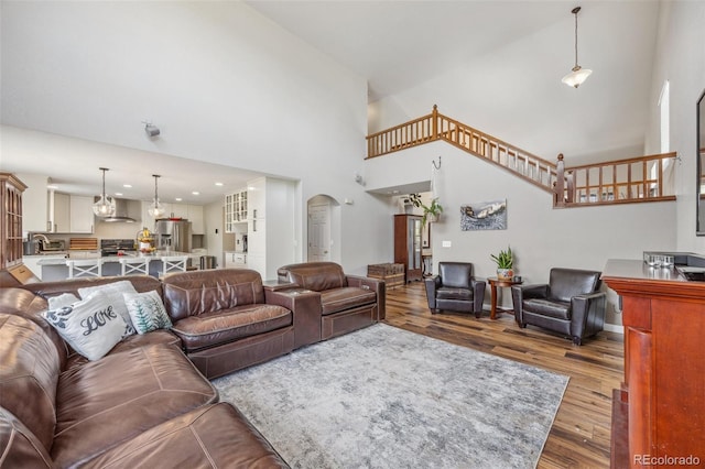 living area with wood finished floors, a high ceiling, and arched walkways