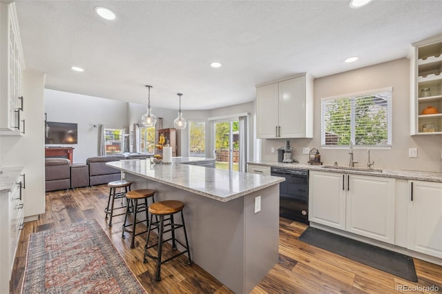 kitchen featuring black dishwasher, a sink, white cabinets, a kitchen breakfast bar, and recessed lighting