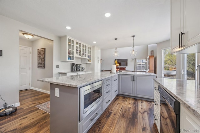 kitchen featuring stainless steel microwave, dishwasher, glass insert cabinets, dark wood-style flooring, and gray cabinets