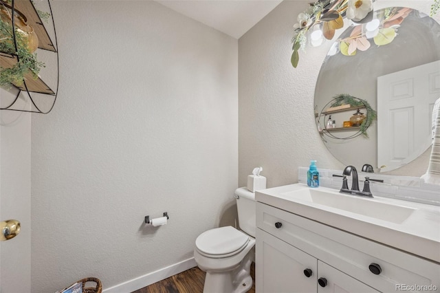 bathroom featuring toilet, wood finished floors, baseboards, and vanity