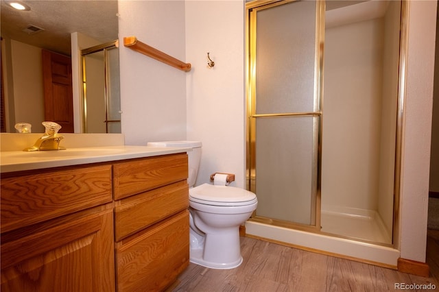 full bathroom with visible vents, a shower stall, wood finished floors, vanity, and toilet