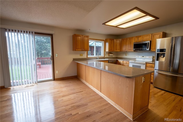 kitchen featuring appliances with stainless steel finishes, plenty of natural light, and light wood-style flooring