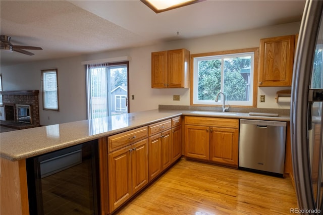 kitchen featuring a ceiling fan, stainless steel dishwasher, a sink, a peninsula, and beverage cooler