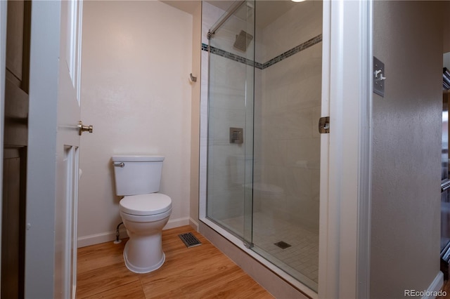 full bathroom featuring toilet, baseboards, a shower stall, and wood finished floors