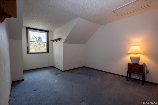 bonus room featuring carpet flooring, a textured ceiling, attic access, lofted ceiling, and visible vents