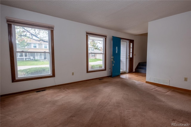 carpeted empty room with stairway, baseboards, and visible vents