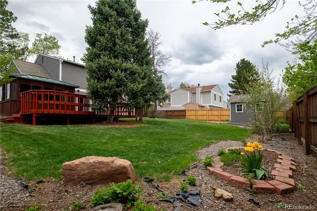 view of yard with an outbuilding, a wooden deck, a fenced backyard, and a storage unit