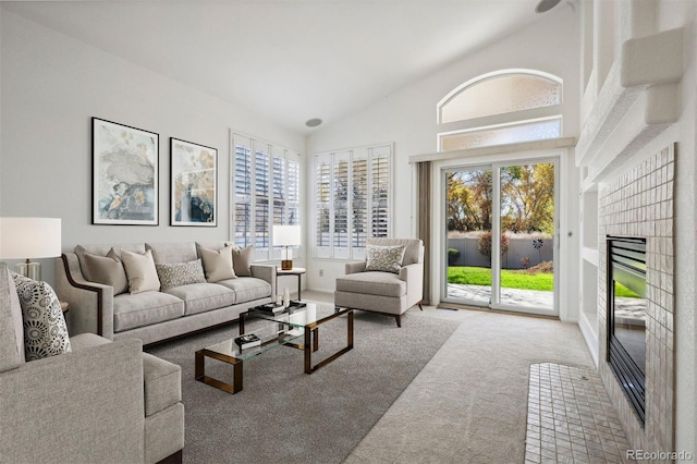 carpeted living room with plenty of natural light, a fireplace, and high vaulted ceiling