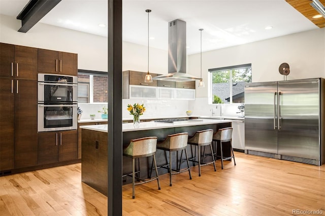 2669 N Cherry St, Denver, CO 80207 - kitchen featuring appliances with stainless steel finishes, island exhaust hood, light wood-style floors, light countertops, and recessed lighting