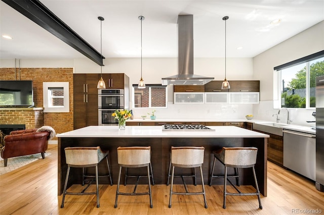 2669 N Cherry St, Denver, CO 80207 - kitchen featuring stainless steel appliances, island range hood, a sink, a spacious island, and modern cabinets